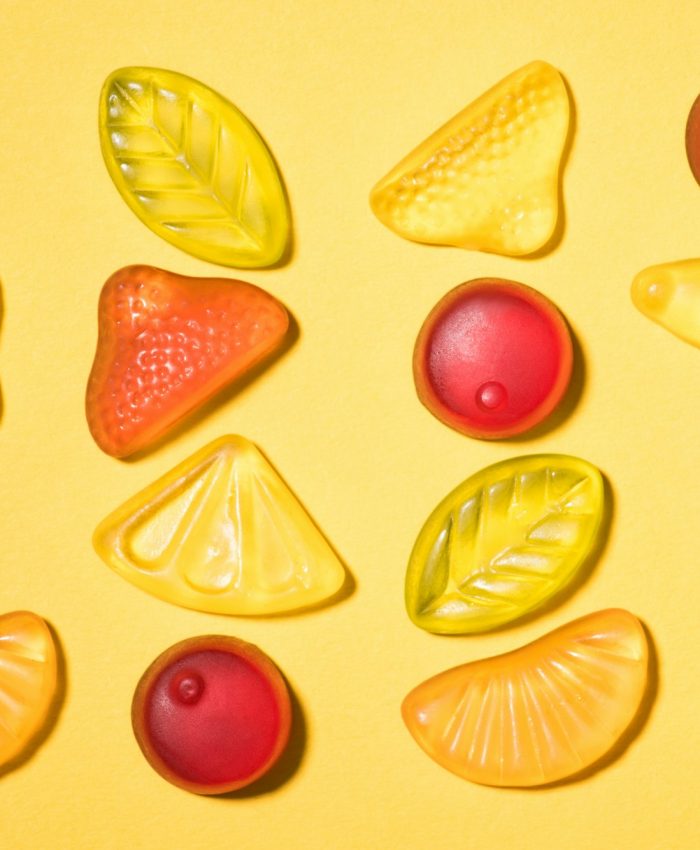 top view of various gummy fruits on yellow surface